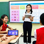 **Prompt:** A dynamic and vibrant modern English language classroom in Vietnam. Vietnamese students, a mix of boys and girls aged 10-15, are actively engaged, using tablets and smartphones for interactive learning games and quizzes. A Vietnamese female teacher stands at the front, enthusiastically guiding them, with an interactive whiteboard displaying colorful, game-like elements. The atmosphere is energetic, collaborative, and full of smiles. Bright, contemporary classroom design with plenty of natural light, showcasing student-centered learning and seamless technology integration.